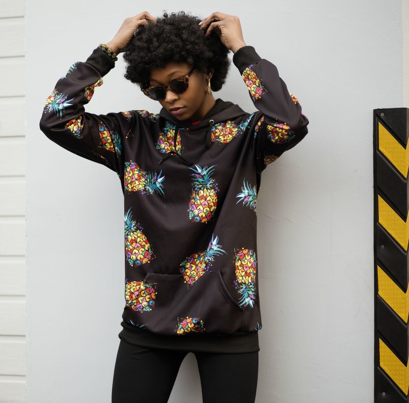 Fashionable young woman posing in a pineapple print hoodie, exuding casual street style.